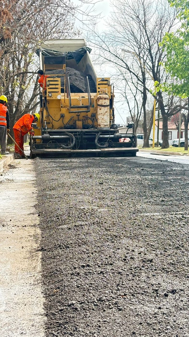 Terminadora de asfalto y cuadrilla trabajando en una calle urbana