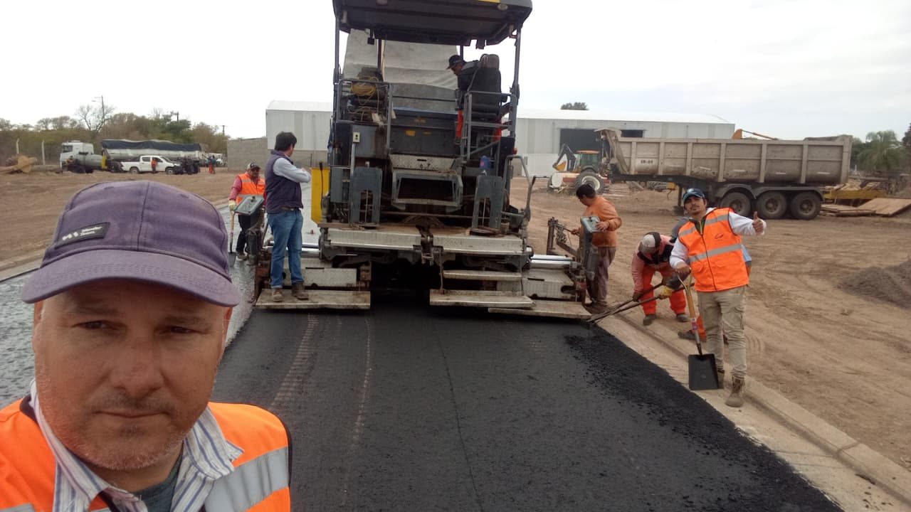 Equipo de TPA Construcciones junto a la terminadora de asfalto en obra